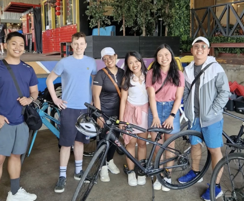 a group smiling to the camera with a bike on their front